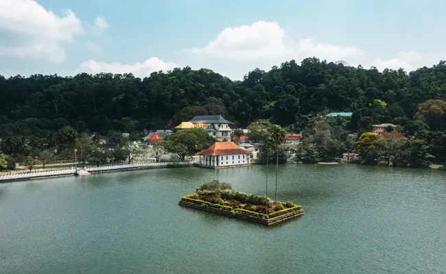 The sacred Temple of the Tooth in Kandy against a backdrop of green hills.